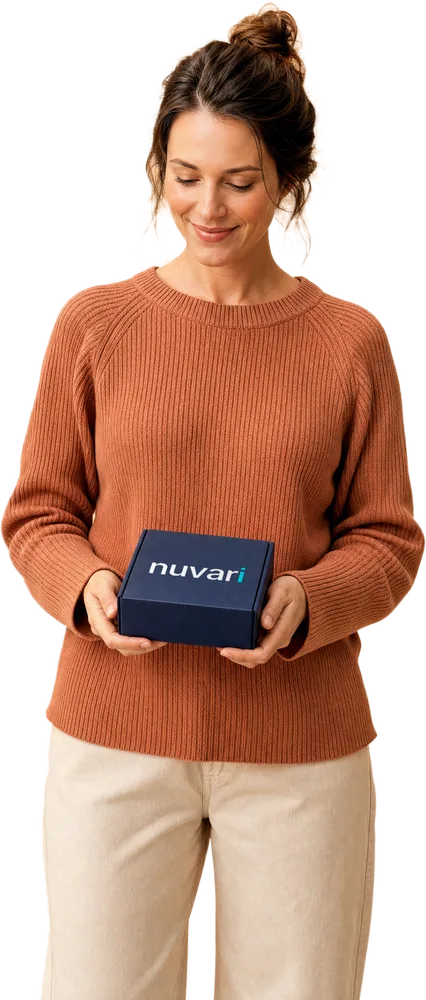 A woman in a terracotta knit holding a navy Nuvari shipping box to her chest — one delivery for the whole quarter