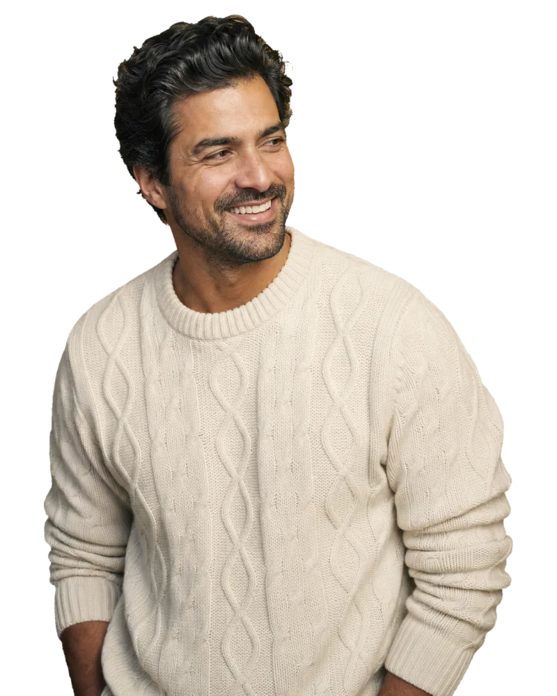 A smiling man with thick, healthy hair in a cream knit sweater on the CROWN Protocol